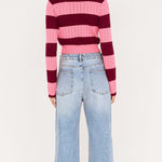 Person wearing a striped sweater and jeans on a white background