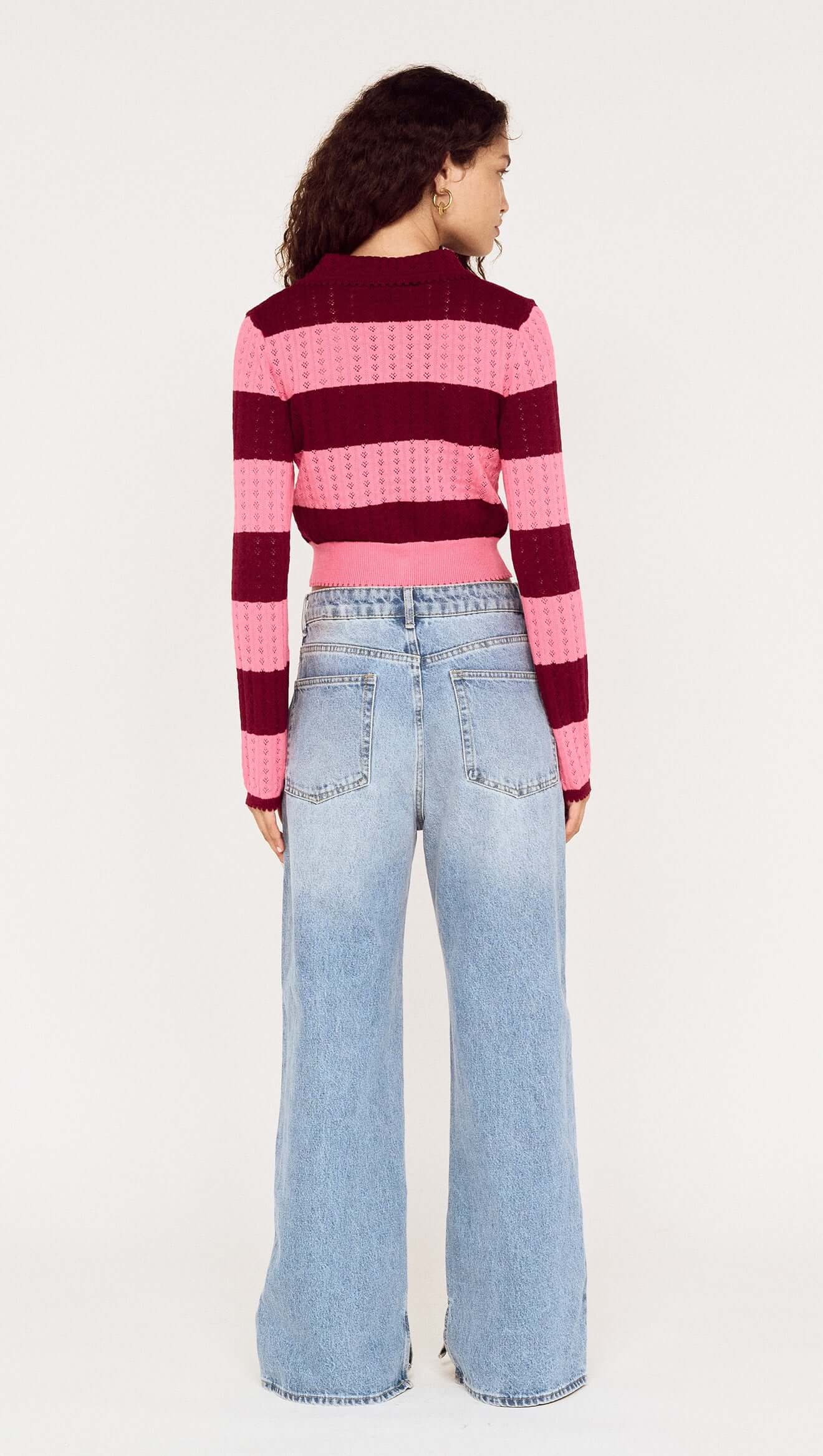 Person wearing a striped sweater and jeans on a white background