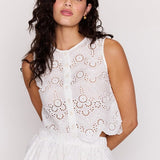 Woman wearing a white lace dress against a plain background