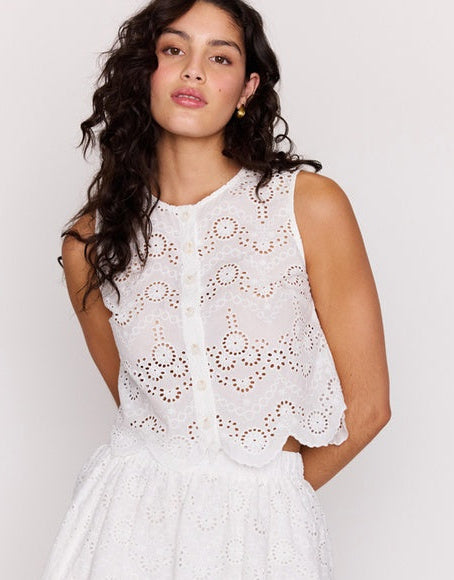 Woman wearing a white lace dress against a plain background