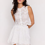 Woman wearing a white lace dress against a plain background