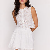 Woman wearing a white lace dress against a plain background