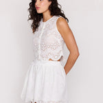 Woman wearing a white lace dress against a plain background