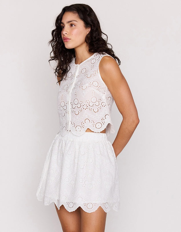 Woman wearing a white lace dress against a plain background
