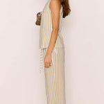 Woman wearing a striped jumpsuit against a plain background