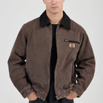 Man wearing a brown jacket with a visible brand logo on a white background