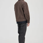 Man wearing a brown jacket and dark jeans on a white background