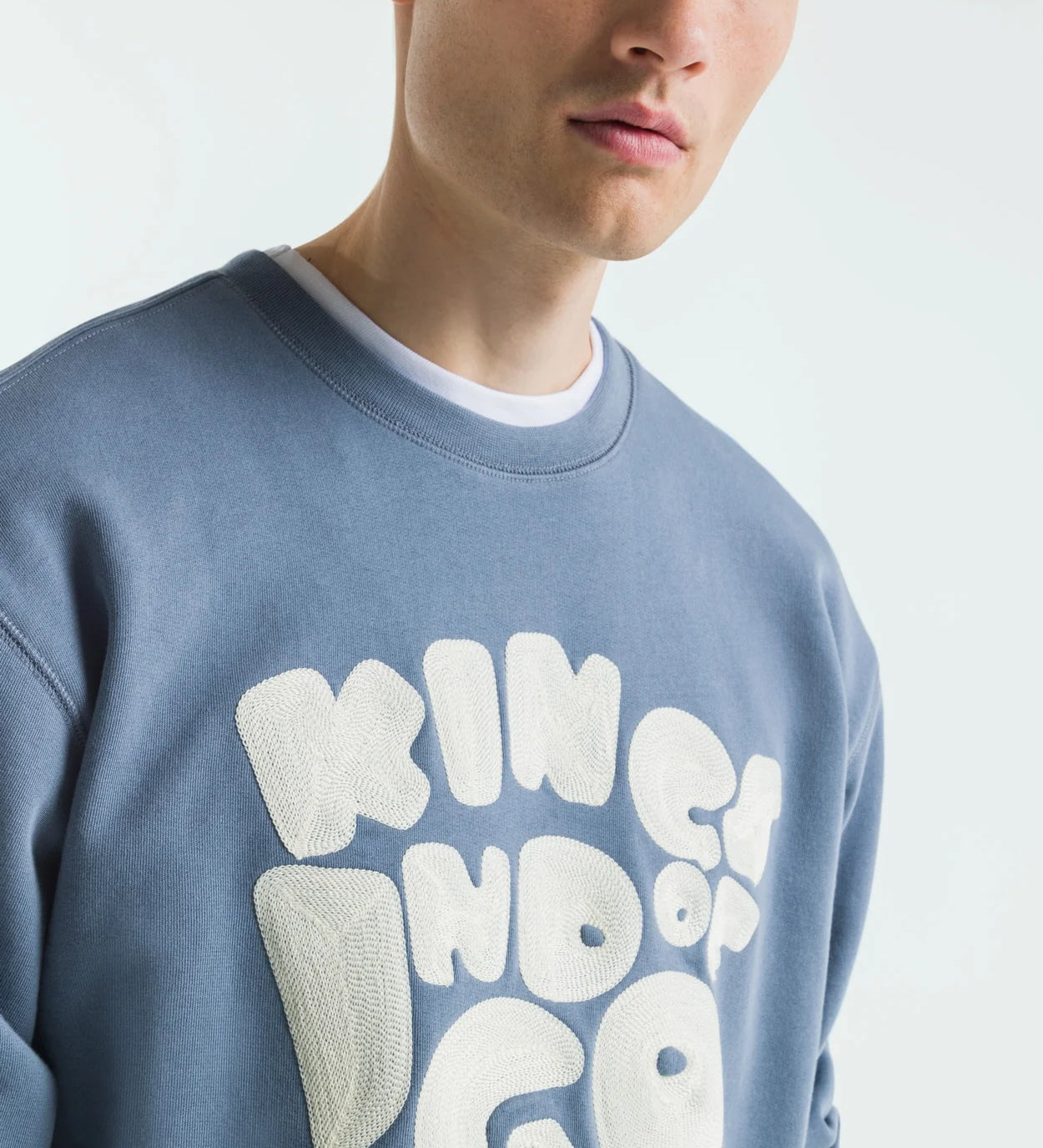 Man wearing a blue sweatshirt with white text on a plain background