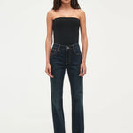 Woman wearing a black strapless top and dark blue jeans on a white background