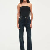 Woman wearing a black strapless top and dark blue jeans on a white background