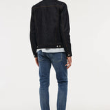 A man viewed from behind wearing a black denim jacket, a white and blue striped shirt, blue jeans, and black shoes, standing against a plain white studio background.