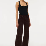 A model wearing dark brown wide-leg corduroy pants and a black tank top, standing against a plain white studio background.