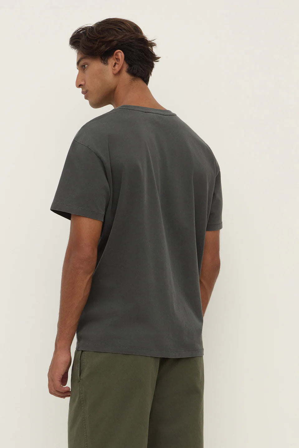 Man wearing a dark green t-shirt and pants against a white background