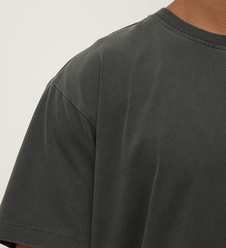 Dark gray t-shirt worn by a person on a light gray background