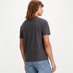 Person wearing a dark gray t-shirt and blue jeans on a white background