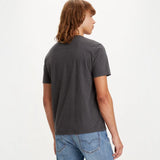Person wearing a dark gray t-shirt and blue jeans on a white background