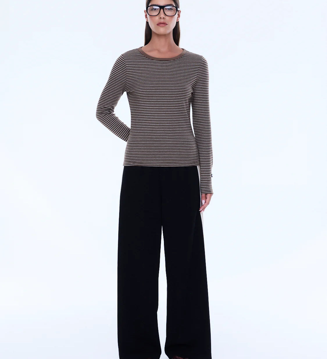 Woman wearing a striped sweater and black pants on a white background