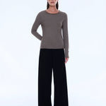 Woman wearing a striped sweater and black pants on a white background