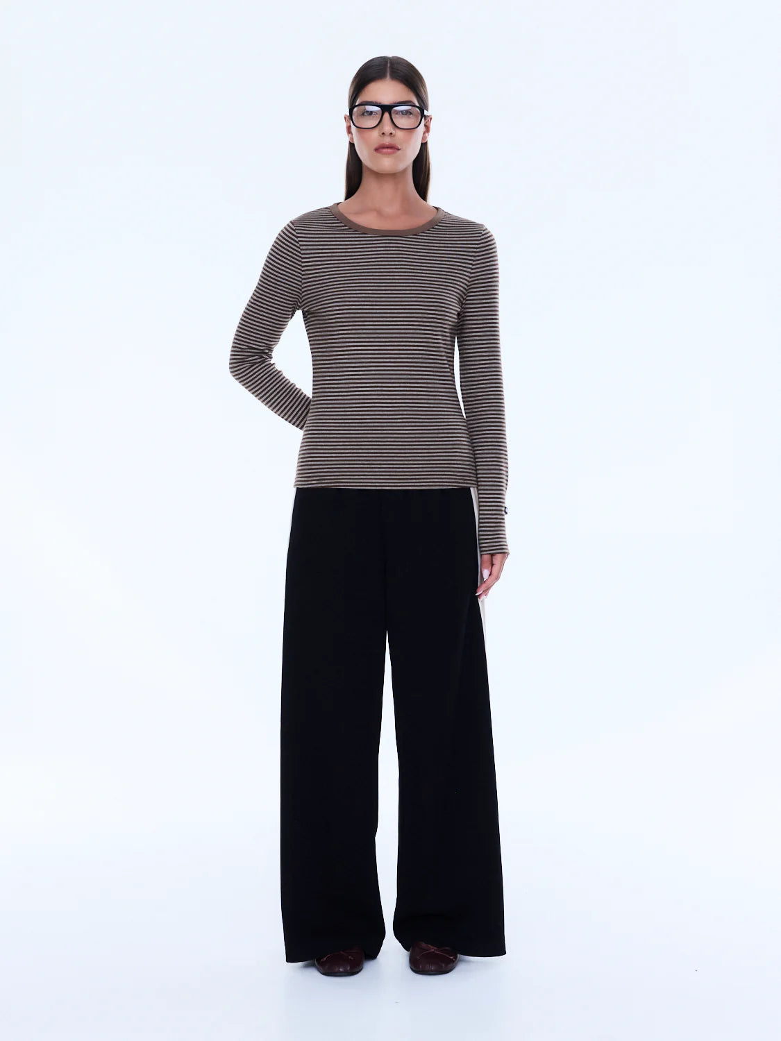 Woman wearing a striped sweater and black pants on a white background
