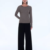 Woman wearing a striped sweater and black pants on a white background