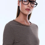 Woman wearing black glasses and a striped shirt against a white background