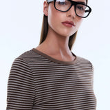 Woman wearing black glasses and a striped shirt against a white background