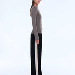 Woman wearing a striped sweater and black pants with white stripes on a white background
