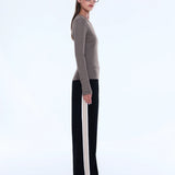 Woman wearing a striped sweater and black pants with white stripes on a white background