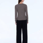 Woman wearing a striped long-sleeve top and black pants on a white background
