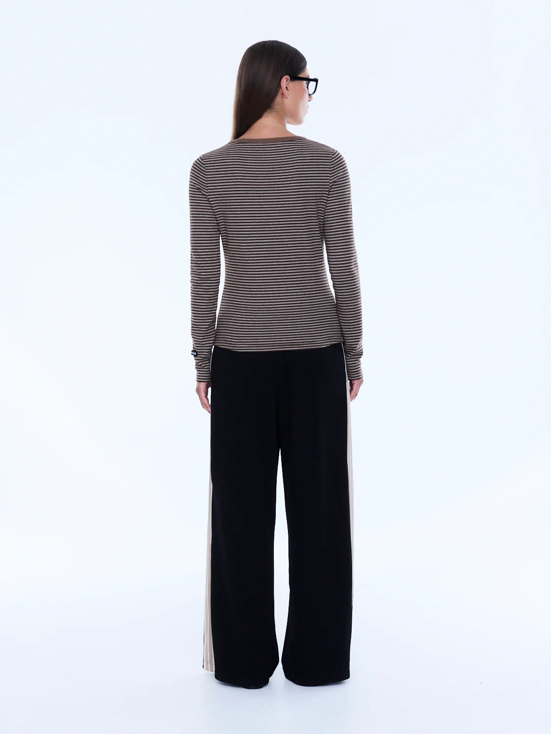 Woman wearing a striped long-sleeve top and black pants on a white background