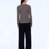 Woman wearing a striped long-sleeve top and black pants on a white background
