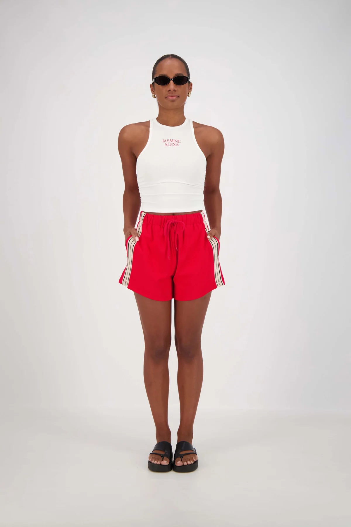 A person standing wearing red and white shorts with a drawstring waist and white top.