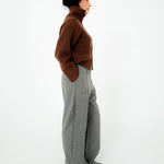Person wearing a brown sweater and gray pants on a white background