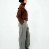 Person wearing a brown sweater and gray pants on a white background