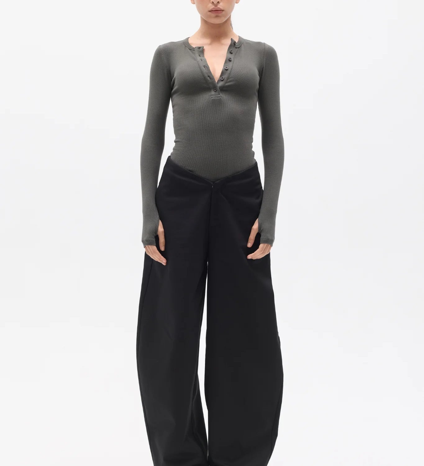 Woman wearing a gray long-sleeve top and black pants on a white background