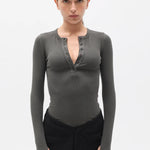 Woman wearing a dark gray long-sleeve top with a V-neckline on a white background