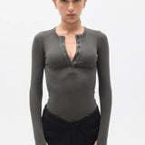 Woman wearing a dark gray long-sleeve top with a V-neckline on a white background
