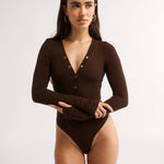 Woman wearing a brown bodysuit on a white background