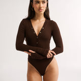 Woman wearing a brown bodysuit on a white background