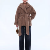 Woman wearing a brown teddy coat on a white background