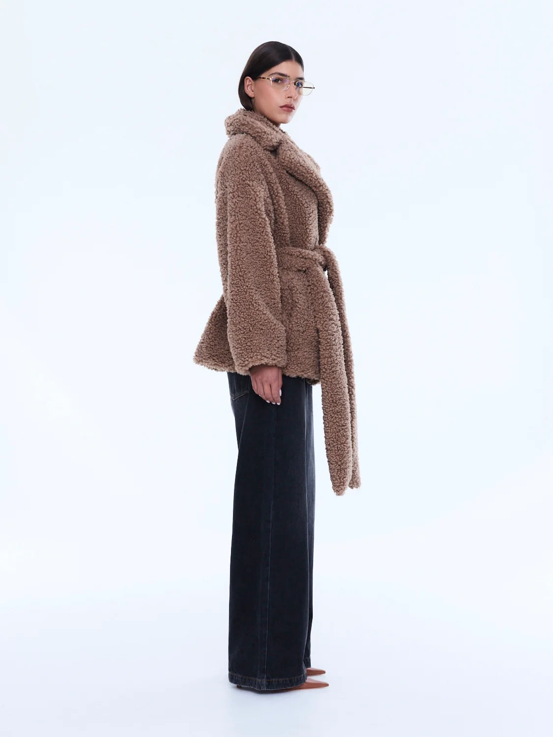 Woman wearing a brown teddy coat on a white background