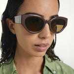 Woman wearing brown sunglasses with a green shirt on a white background