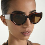 Close-up of a person wearing tortoiseshell sunglasses with a white frame.