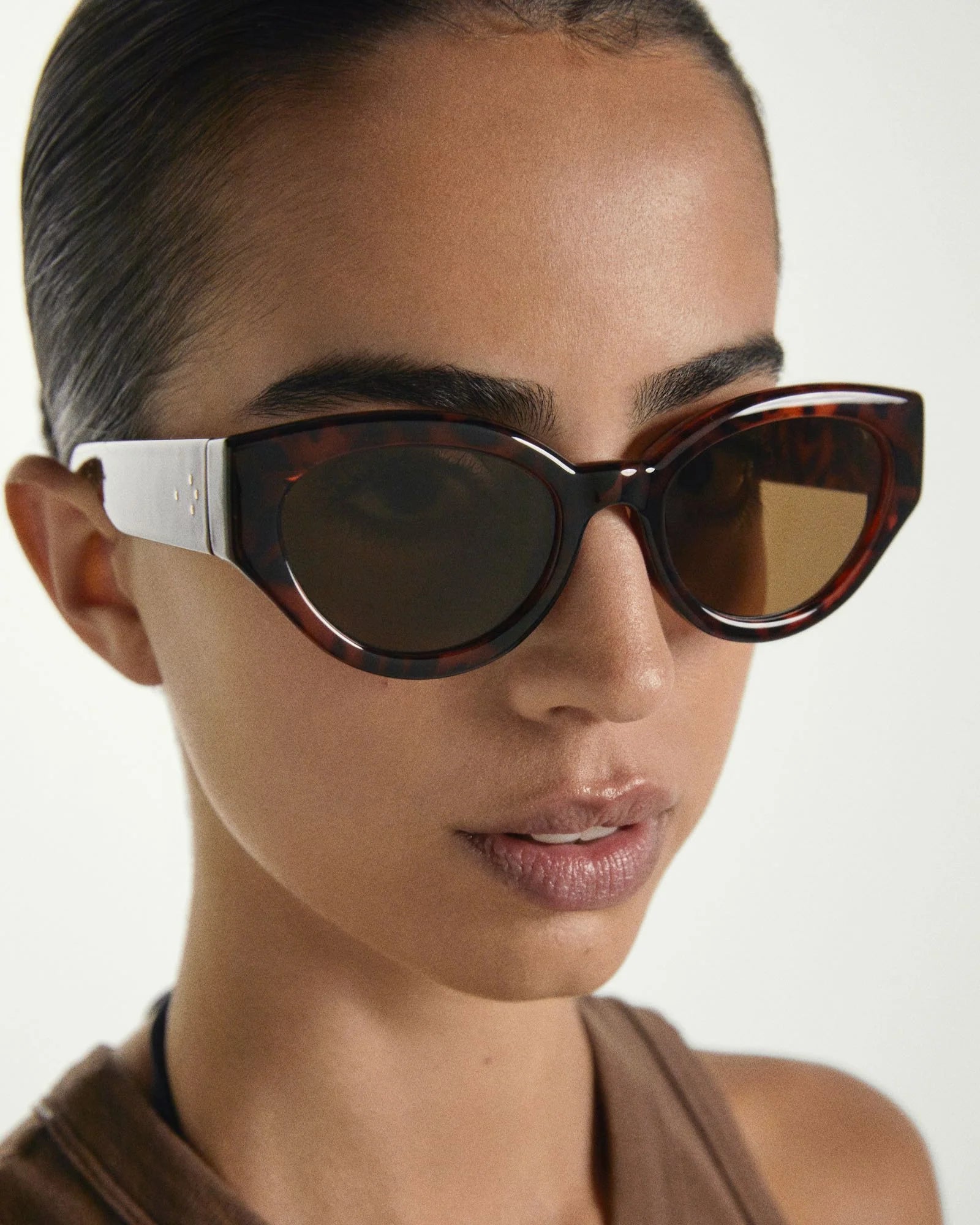 Close-up of a person wearing tortoiseshell sunglasses with a white frame.