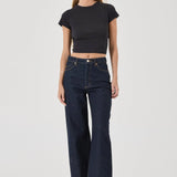 Woman wearing a black crop top and dark blue jeans on a white background