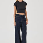 Woman wearing dark blue jeans and a black crop top on a white background