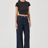 Woman wearing dark blue jeans and a black crop top on a white background