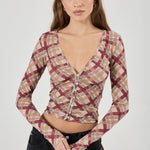 Woman wearing a plaid long-sleeve top against a white background