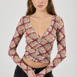 Woman wearing a plaid long-sleeve top against a white background