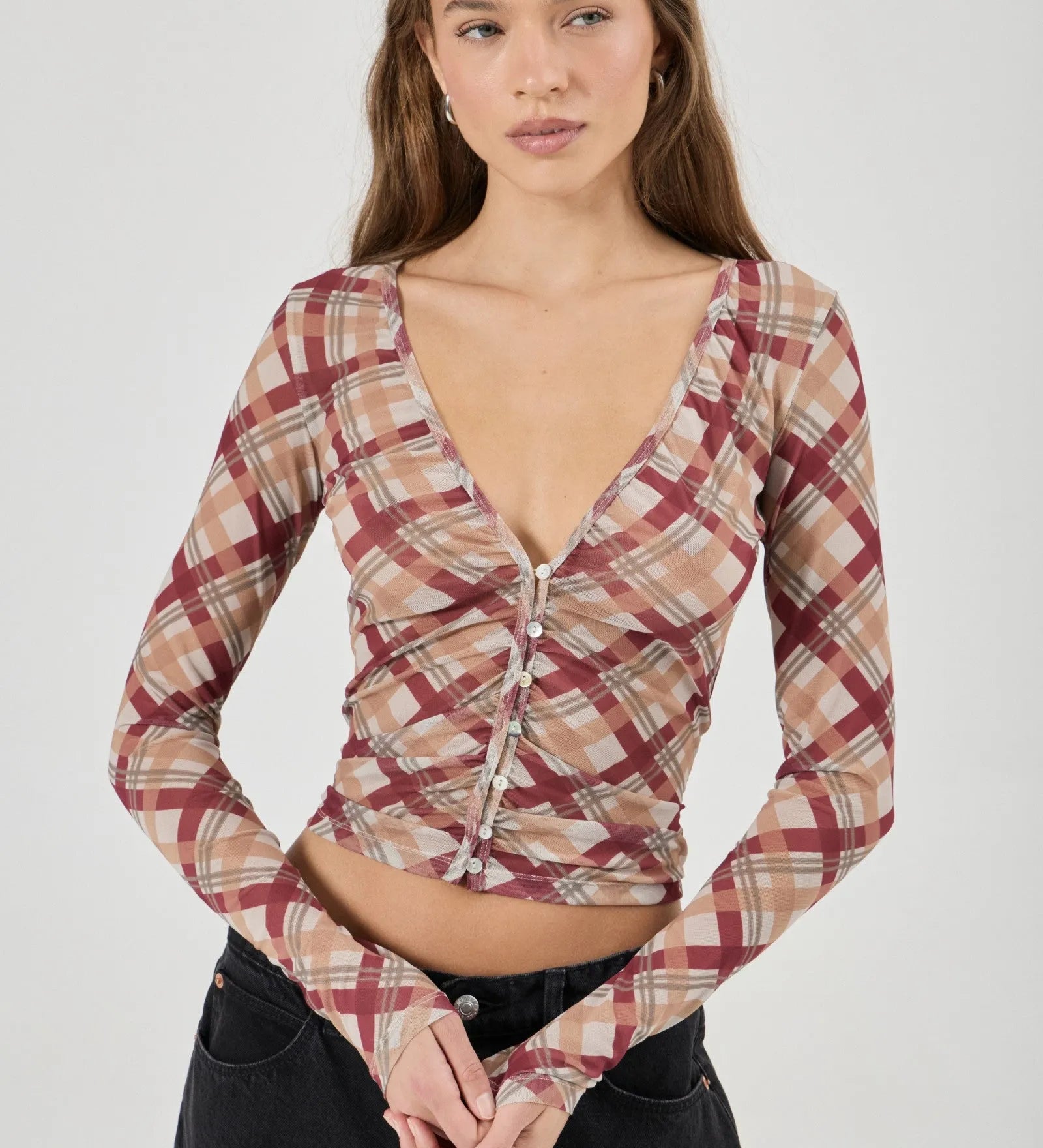 Woman wearing a plaid long-sleeve top against a white background
